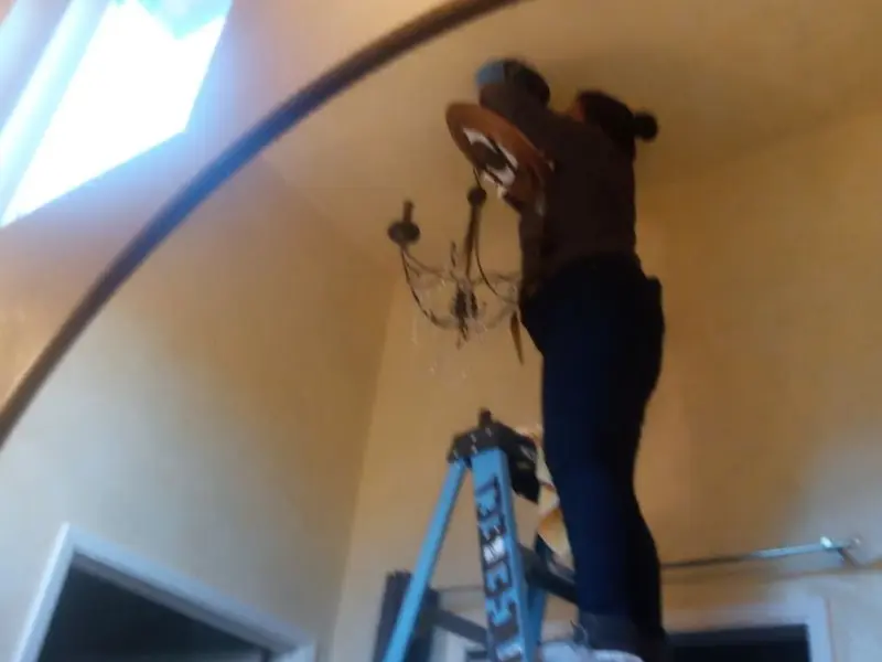 Electrician installing a chandelier in a Piney residence